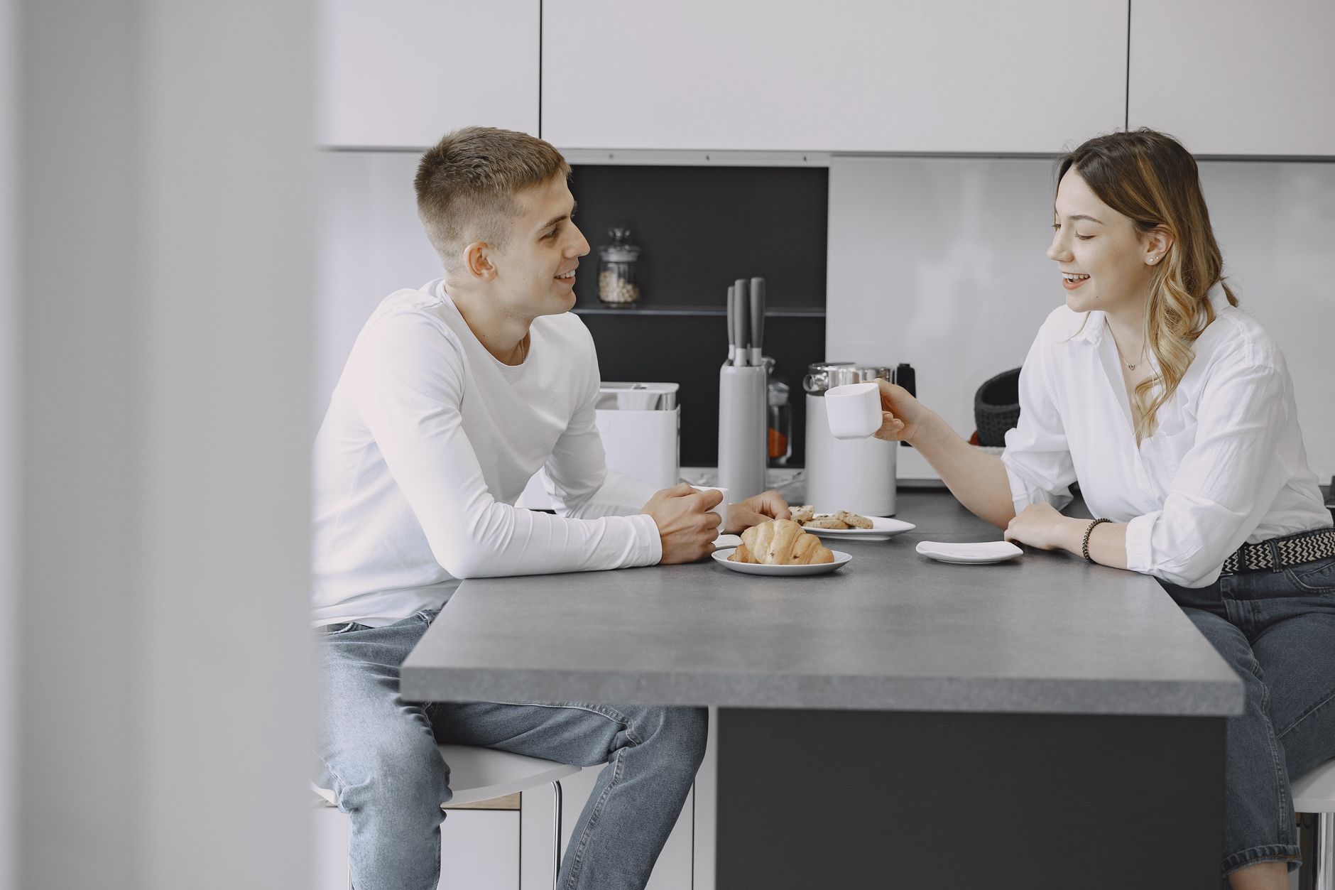 Een stel zit aan het keukenblad met koffie en praat ontspannen met elkaar